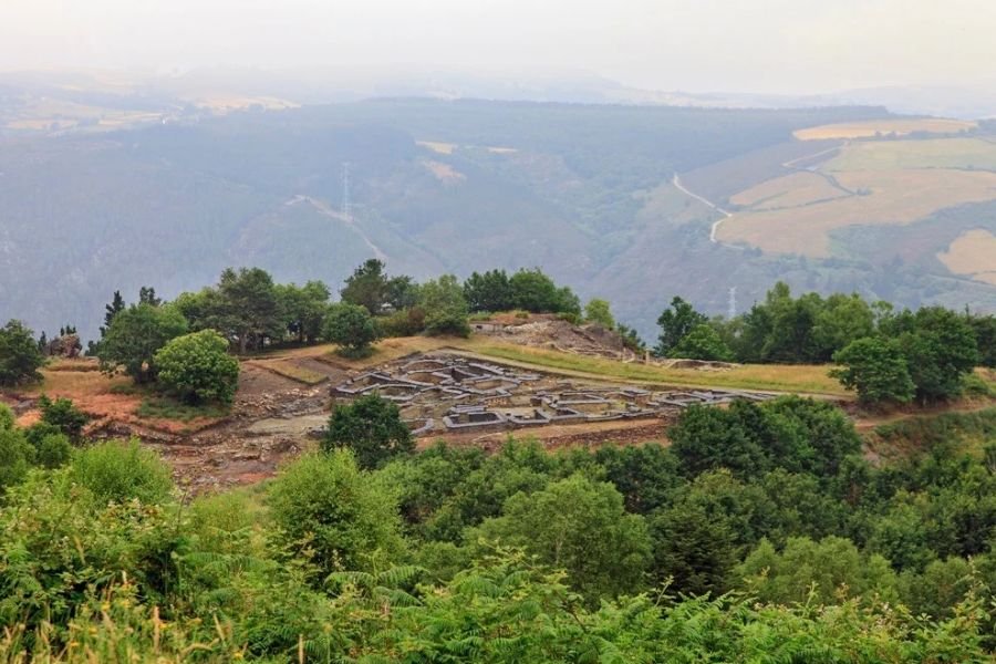 Die Ruinen der Wallburg Chao Samartín auf einem Hügel, dahinter Täler und Berge