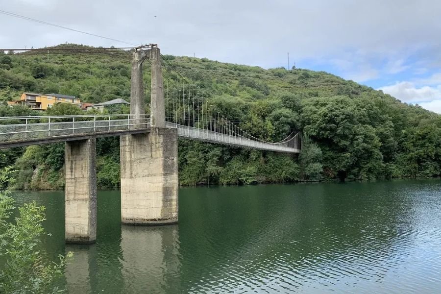 Eine Fußgänger-Hängebrücke auf hohen Betonpfeilern über den Sil in O Barco de Valdeorras