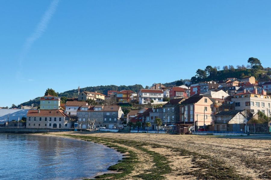 Bunte Häuser über einem Sandstrand in Redondela an der Ría von Vigo