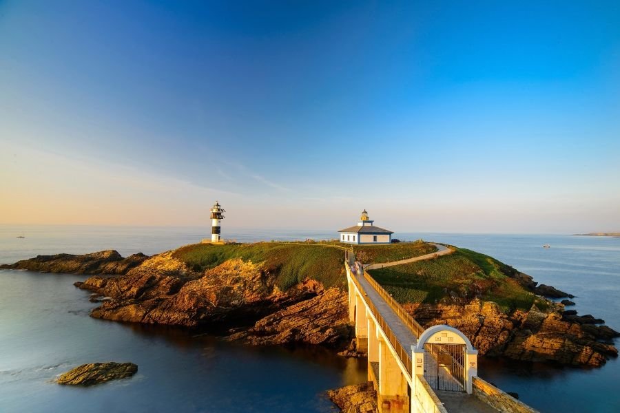 Die beiden Leuchttürme der Illa Pancha in Ribadeo, über eine Brücke mit der Küste verbunden, bei Sonnenuntergang