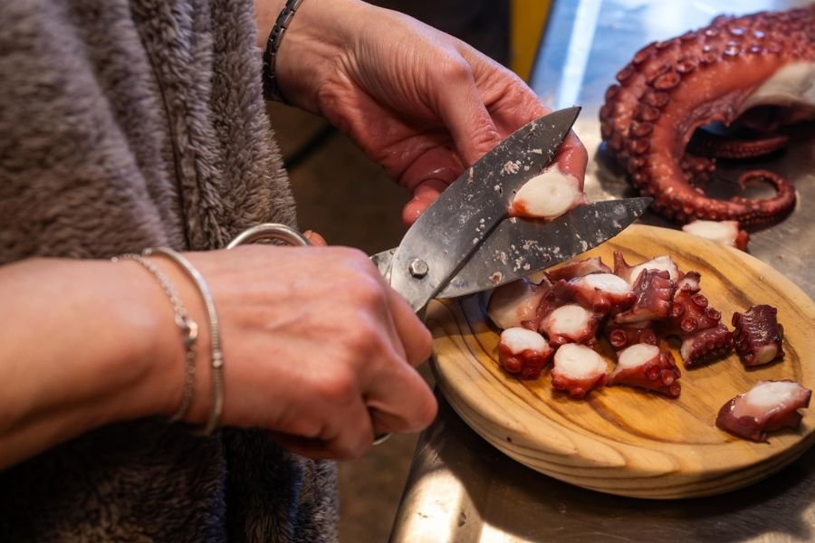 Pulpo á feira wird in Melide mit der Schere auf einen Holzteller geschnitten