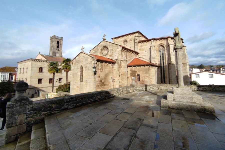 Chiese gotiche medievali in pietra con rosoni e un cruceiro su una piazza lastricata nel centro storico di Betanzos
