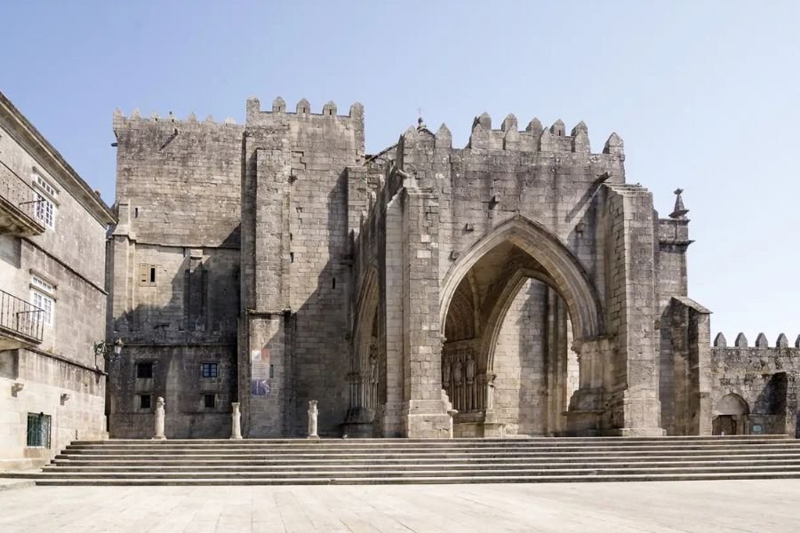 La fachada de piedra almenada y el pórtico gótico de la Catedral de Tui
