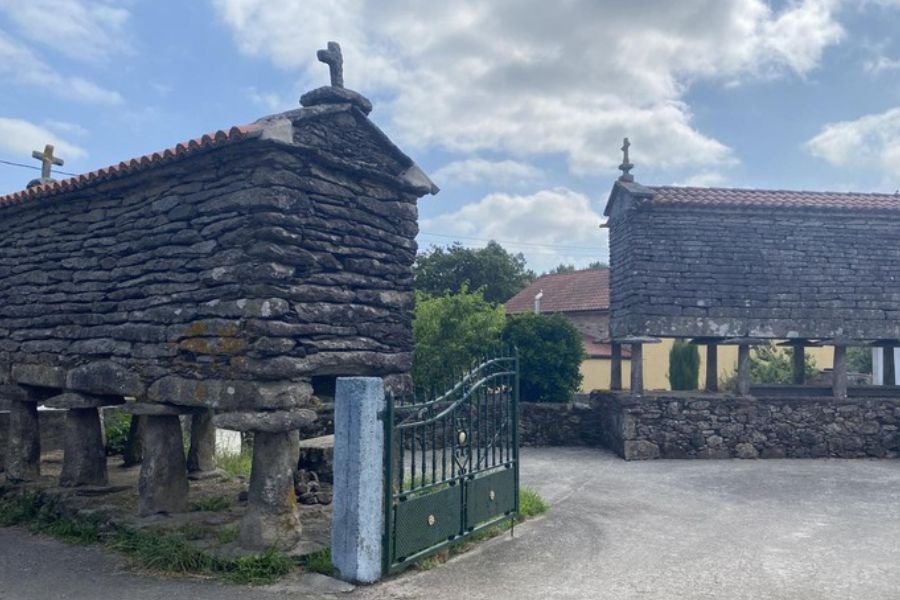 Two traditional stone hórreos, the raised granaries of Galicia, topped with crosses in As Maroñas