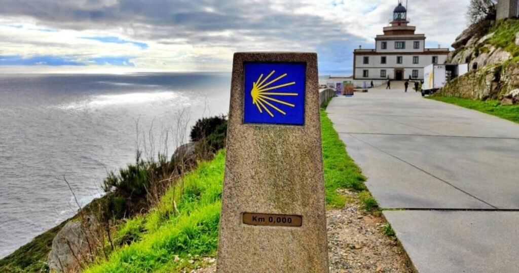 The 0.000 km marker of the Camino de Santiago at Cape Finisterre, with the lighthouse and the Atlantic Ocean behind it