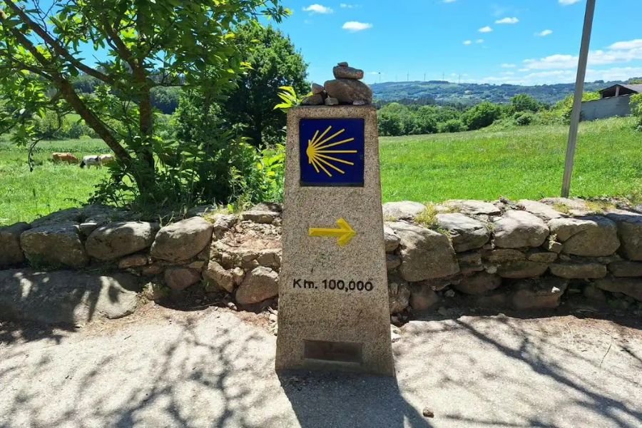 The km 100 waymarker on the Camino Frances, with the scallop shell and yellow arrow, shortly after Sarria